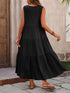 Woman wearing a black sleeveless dress with a layered skirt, standing outdoors.